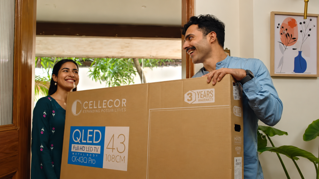 Cellecor campaign showing a couple carrying a television box through a home.