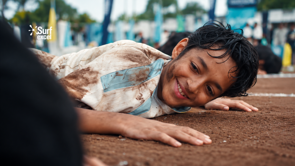 Surf Excel campaign showing a smiling child on a muddy sports ground.